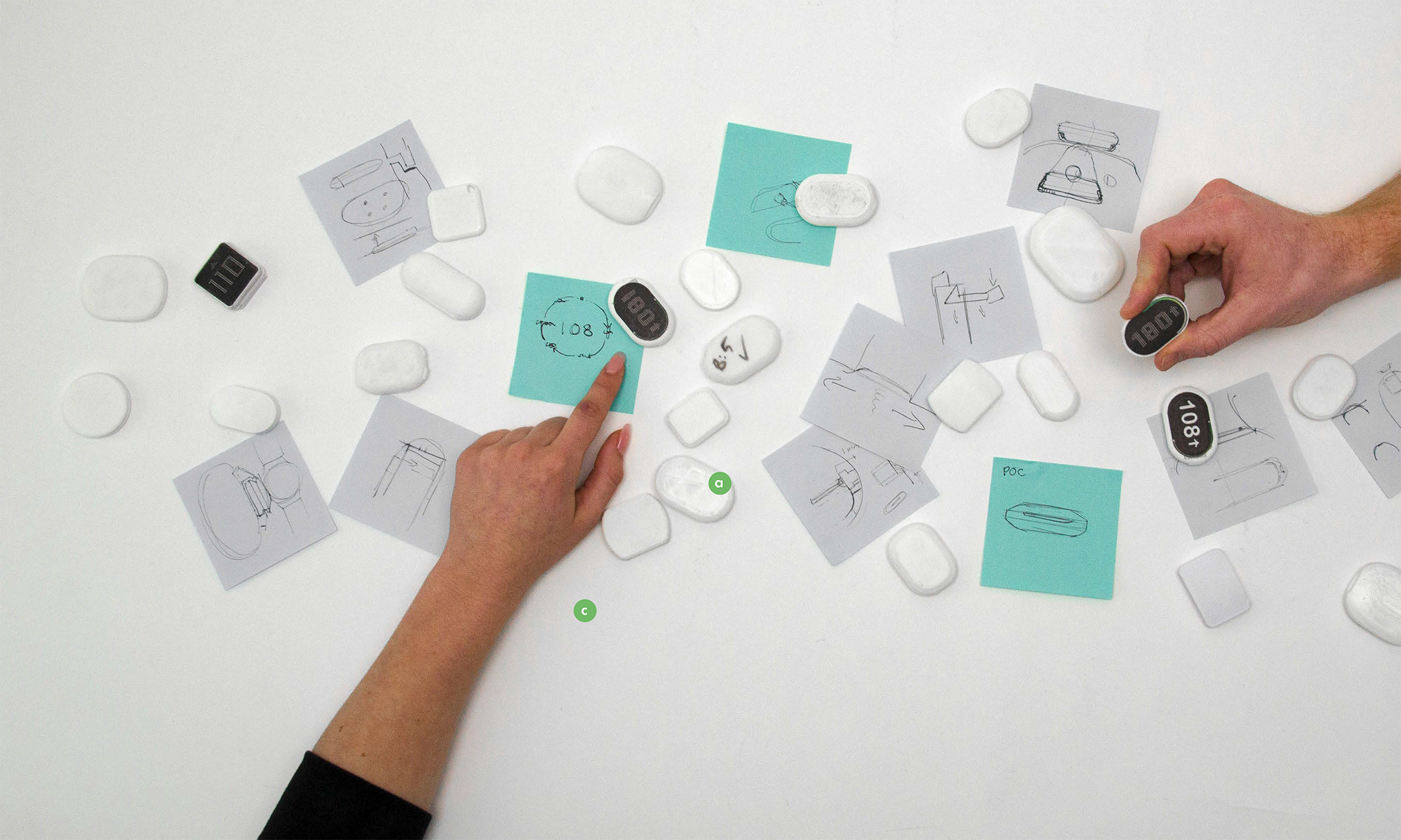 An overhead view of a table with models and post-it sketches.